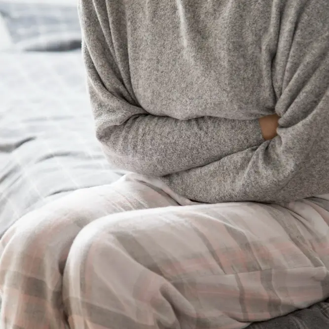 Pharmacy First UTI - Urinary Tract Infections - Woman holding her stomach in pain